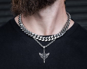 May include: A silver chain necklace with a silver pendant shaped like a moth with a sword for a body. The necklace is layered over a thicker silver chain.