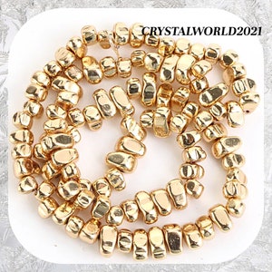 Peut inclure: Un brin de perles dorées en forme de pépites. Les perles sont de forme irrégulière et ont une finition brillante et métallique.