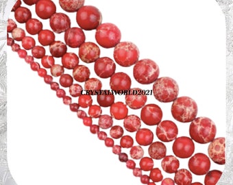 May include: A strand of red and white marbled gemstone beads in various sizes. The beads are round and have a speckled appearance.