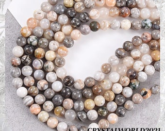 May include: Strands of gemstone beads in various colors, including white, gray, tan, and peach. The beads are round and appear to be made of natural stone. The text "CRYSTALWORLD2021" is visible in the bottom right corner. These beads are suitable for jewelry making.