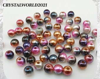 May include: A collection of iridescent round beads in various shades of pink, purple, gold, and black. The beads have a pearlescent finish and are perfect for jewelry making or crafting.