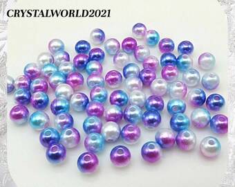 May include: A collection of iridescent round beads in shades of blue, purple, and white. The beads have a pearlescent finish and are perfect for crafting.