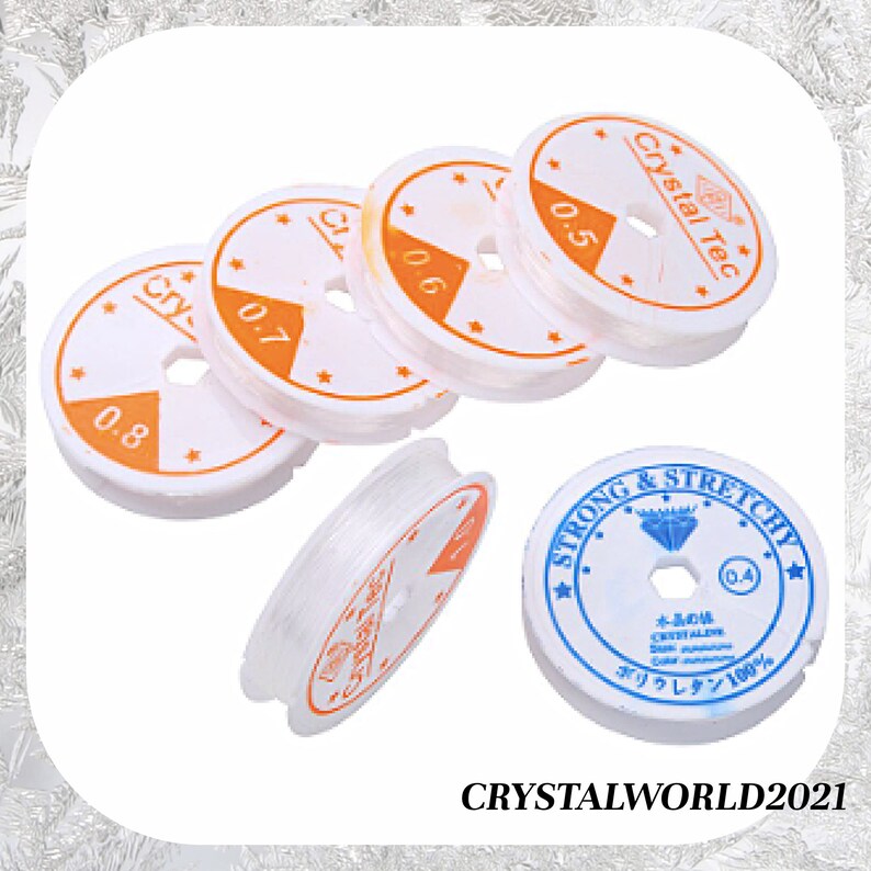 May include: Five spools of clear elastic string for jewelry making. The spools are white with orange and black text that reads "Crystal Tec" and "Strong & Stretchy". The spools are labeled with different sizes: 0.4, 0.5, 0.6, 0.7, and 0.8.