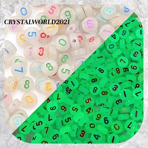 May include: Two piles of plastic number beads. One pile is white with colorful numbers and the other pile is green with black numbers.