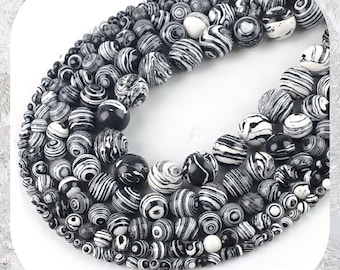 May include: A strand of black and white striped round beads. The beads are made of natural stone and have a polished finish.