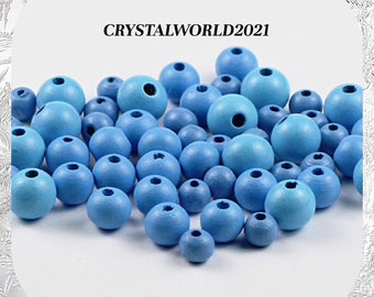 May include: A large group of light blue wooden beads. The beads are round and have a hole in the center. The beads are arranged in a random pattern.  CRYSTALWORLD2021