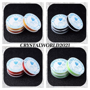 May include: Four spools of elastic string for jewelry making. The spools are labeled "Strong & Stretchy" and have a diamond logo. The spools are in the colors yellow, black, red, and green.