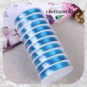 May include: A roll of turquoise blue elastic string for jewelry making. The string is wound around a white spool and is packaged in clear plastic.