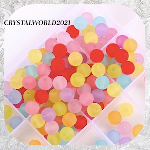 May include: A selection of pastel coloured round beads in a clear plastic storage container. The beads are translucent and have a frosted finish. The colours include pink, yellow, blue, green, and red.