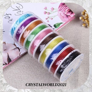 May include: A set of eight spools of elastic string in various colors, including blue, purple, orange, green, pink, brown, yellow, red, and black. The spools are wrapped in clear plastic and labeled with the text "CRYSTALWORLD2021".