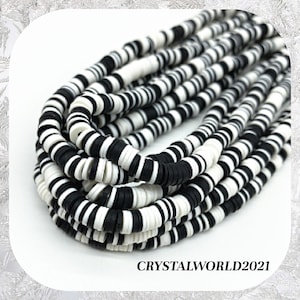 May include: A close-up of a pile of black and white disc-shaped beads. The beads are arranged in strands, displaying a repeating pattern of alternating colours. The text "CRYSTALWORLD2021" is visible at the bottom.