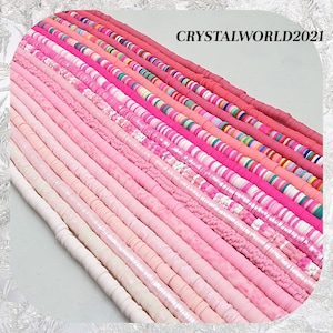 May include: A collection of pink and white polymer clay beads in various shapes and sizes. The beads are arranged in rows, creating a colourful and visually appealing display.  CRYSTALWORLD2021 is printed in the top right corner of the image.