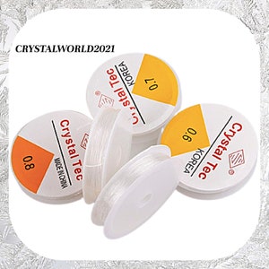 May include: Four spools of clear elastic thread, each with a yellow label that reads "Crystal Tec" and "KOREA". The labels also indicate the thread thickness: 0.6, 0.7, and 0.8 mm. One spool has a label that reads "Crystal Tec" and "MADE IN CHINA".