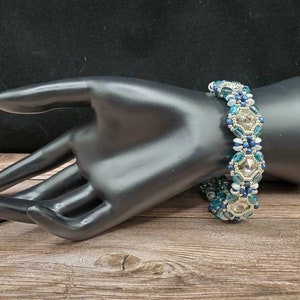 May include: A beaded bracelet with blue, white, and silver beads in a geometric pattern.