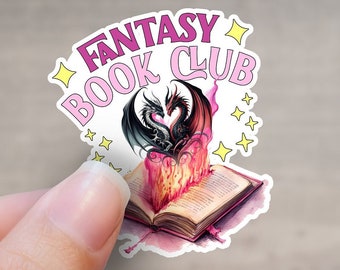 Può includere: Un adesivo con un design rosa e bianco che presenta due draghi neri intrecciati a forma di cuore sopra un libro aperto con fiamme. Il testo "Fantasy Book Club" è scritto in lettere rosa con stelle gialle.