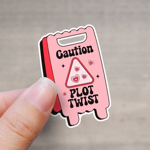 May include: Pink and red caution sign sticker with the text "Caution Plot Twist" and a triangle with hearts inside.