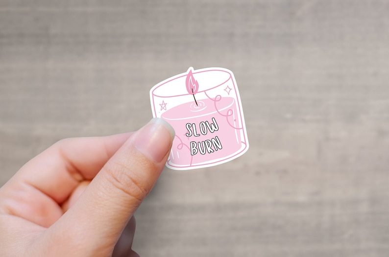 May include: A pink sticker with a candle illustration and the text "Slow Burn".