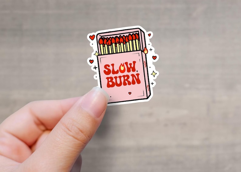 K&ouml;nnte beinhalten: Ein rosa Streichholzschachtel-Aufkleber mit einer roten Flamme und dem Text "SLOW BURN".