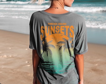 May include: A gray t-shirt with a graphic print of a sunset and palm trees. The text "FOREVER CHASING SUNSETS" is printed on the shirt.