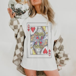 May include: White t-shirt with a vintage-style graphic of the Queen of Hearts playing card. The card has a red heart and a black spade.