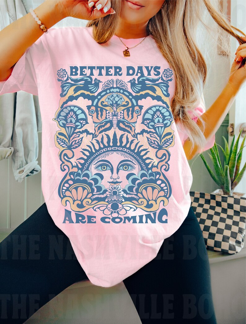 May include: Pink t-shirt with a graphic design featuring a stylized sun with a face and the text "Better Days Are Coming".