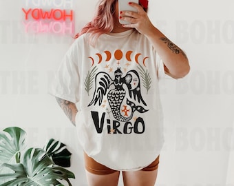 Puede incluir: Camiseta blanca con una ilustración en blanco y negro de una sirena con un diseño de sol y luna. El texto "Virgo" está impreso debajo de la ilustración.