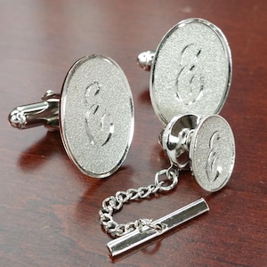May include: Silver cufflinks and a tie tack with a textured finish and the letter "E" engraved on each piece.