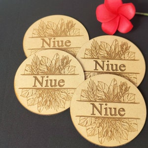 May include: Four round wooden coasters with a tropical leaf design and the word "Niue" engraved on each.