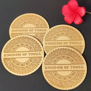 May include: Four round wooden coasters with a decorative design and the words "Kingdom of Tonga" engraved on each. The coasters are brown and have a light brown design.