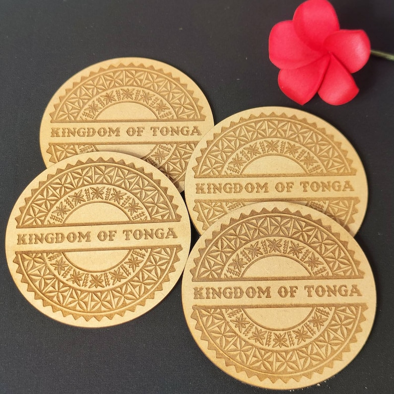 May include: Four round wooden coasters with a decorative design and the words "Kingdom of Tonga" engraved on each. The coasters are brown and have a light brown design.