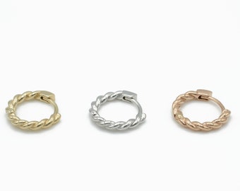 May include: Three small hoop earrings in gold, silver, and rose gold. Each hoop is twisted and has a polished finish.