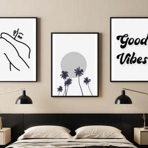 May include: Three framed art prints. The left print features a minimalist line drawing of a person. The center print shows a gray sun and palm trees. The right print displays the words "Good Vibes" in a retro font. All prints have black frames.