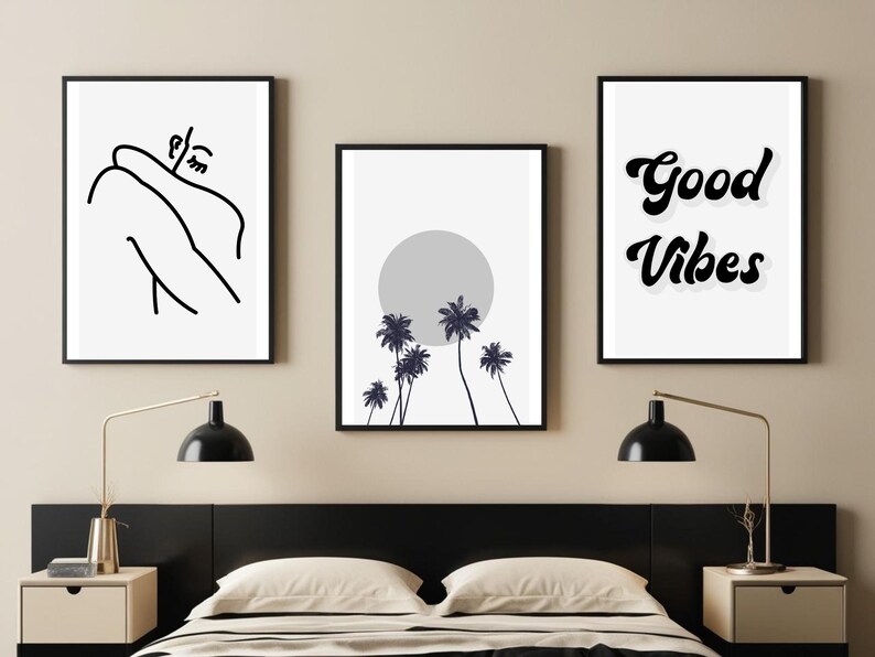 May include: Three framed art prints. The left print features a minimalist line drawing of a person. The center print shows a gray sun and palm trees. The right print displays the words "Good Vibes" in a retro font. All prints have black frames.