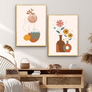 K&ouml;nnte beinhalten: Zwei minimalistische Kunstdrucke mit beigefarbenem Hintergrund. Der erste Druck zeigt eine Linienzeichnung eines Gesichts mit einer braunen und t&uuml;rkisfarbenen abstrakten Form. Der zweite Druck zeigt einen Strau&szlig; rosa und gelber Blumen in braunen und t&uuml;rkisfarbenen Vasen.