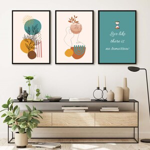 K&ouml;nnte beinhalten: Drei gerahmte Drucke mit abstrakten Designs in Braun-, Gelb-, Blaugr&uuml;n- und Rosat&ouml;nen. Der mittlere Druck zeigt eine Linienzeichnung eines Gesichts mit einem Blatt auf dem Kopf. Der rechte Druck hat einen blaugr&uuml;nen Hintergrund mit einer Sanduhr und dem Text "Lebe wie es kein Morgen gibt".