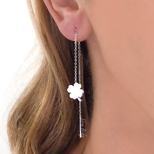 May include: Silver chain earrings with a four-leaf clover charm hanging from the bottom of the chain.