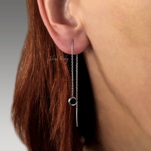 Può includere: Orecchini a catena d'argento con un ciondolo rotondo nero e una barra d'argento che pende dal fondo.
