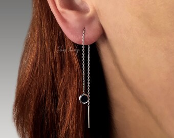 May include: Silver chain earrings with a black circle pendant and a silver bar hanging from the bottom.