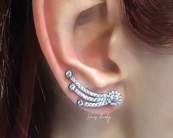 Puede incluir: Pendiente de oreja de plata con un diseño curvo y múltiples piedras de circonita cúbica transparentes. El pendiente se lleva en la parte superior de la oreja.