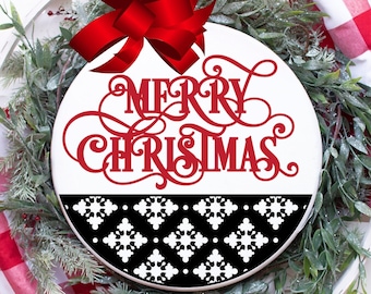 May include: A white round wooden sign with a red bow on top. The sign says "Merry Christmas" in red cursive lettering. The bottom half of the sign has a black and white geometric pattern.