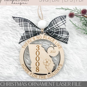 May include: A wooden Christmas bauble with a black and white checked ribbon. The bauble is circular and features the text "There's no place like home for the holidays" and "3008" inside. The year 2022 is also included on the bauble.