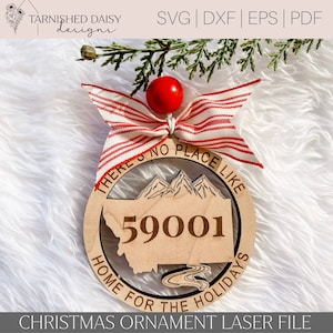 Puede incluir: Adorno navideño de madera con el texto "THERE'S NO PLACE LIKE HOME FOR THE HOLIDAYS" y el número "59001". El adorno presenta un contorno del estado de Montana y un diseño de montaña, con un lazo a rayas rojas y blancas.