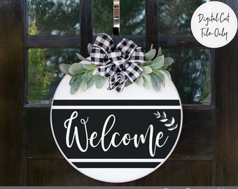 May include: A round welcome sign with black and white stripes and the word "Welcome" in white script. The sign is decorated with a black and white checkered bow and greenery.