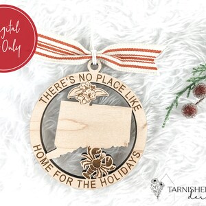 May include: A wooden ornament shaped like the state of Connecticut with the text "There's no place like home for the holidays" around the edge. The ornament is decorated with a floral design and a lobster.