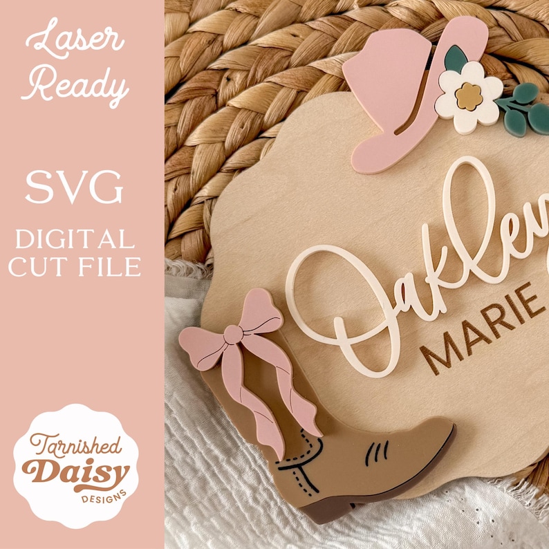 K&ouml;nnte beinhalten: Ein Holzschild mit einem Cowboy-Stiefel, Hut und floralen Akzenten. Der Name "Oakley Marie" ist in einer Schreibschrift dargestellt. Das Schild enth&auml;lt auch den Text "Laser Ready", "SVG DIGITAL CUT FILE" und das Logo "Tarnished Daisy Designs".