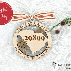 May include: A wooden Christmas ornament featuring a cutout of the state of South Carolina with the text "There's no place like home for the holidays" and the area code "29899".