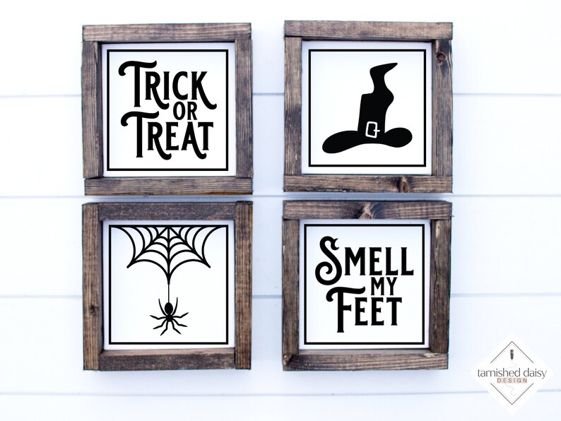 May include: Four wooden framed signs with black Halloween-themed text and images. The signs read "Trick or Treat", "Smell My Feet", a witch's hat, and a spider web with a spider.