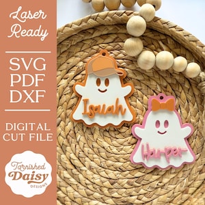 May include: Two ghost-shaped ornaments with personalized names. One ghost wears a baseball cap, the other a bow. The names "Isaiah" and "Harper" are displayed in cursive. The ornaments are white, orange, and pink, with a happy face.