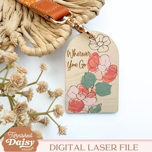 Puede incluir: Un llavero de madera con un dise&ntilde;o floral y el texto "Wherever You Go". El llavero es de color marr&oacute;n claro y tiene un anillo de metal dorado.