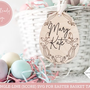 Puede incluir: Una etiqueta de cesta de Pascua de madera cortada con l&aacute;ser en forma de huevo con un dise&ntilde;o floral y los nombres "Mary Kate" escritos en una sola l&iacute;nea.